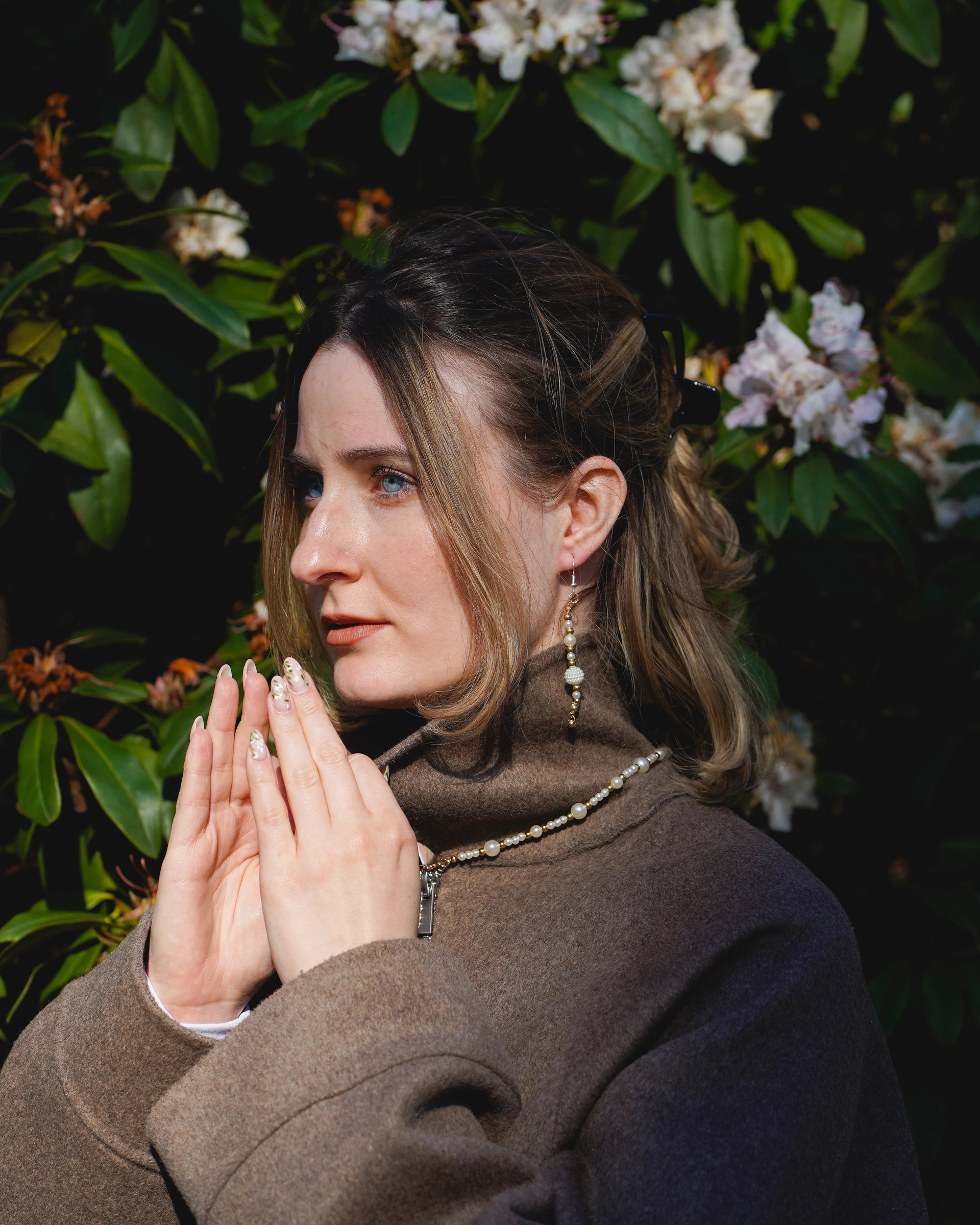 Portrait of a woman wearing pearl jewellery beside flowering greenery by Lunar Lens Creative Agency