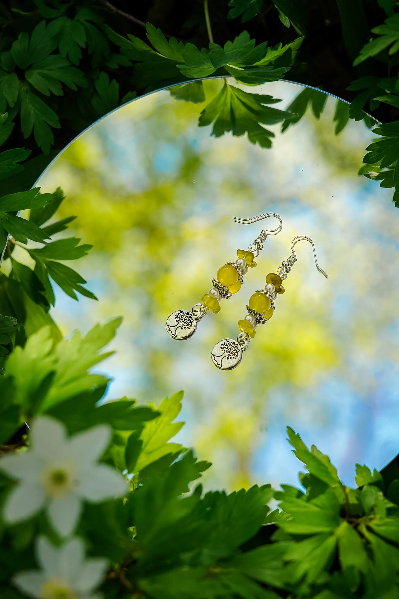 Wildflower Spell yellow bead earrings styled on a mirror among green leaves by Lunar Lens Creative Agency