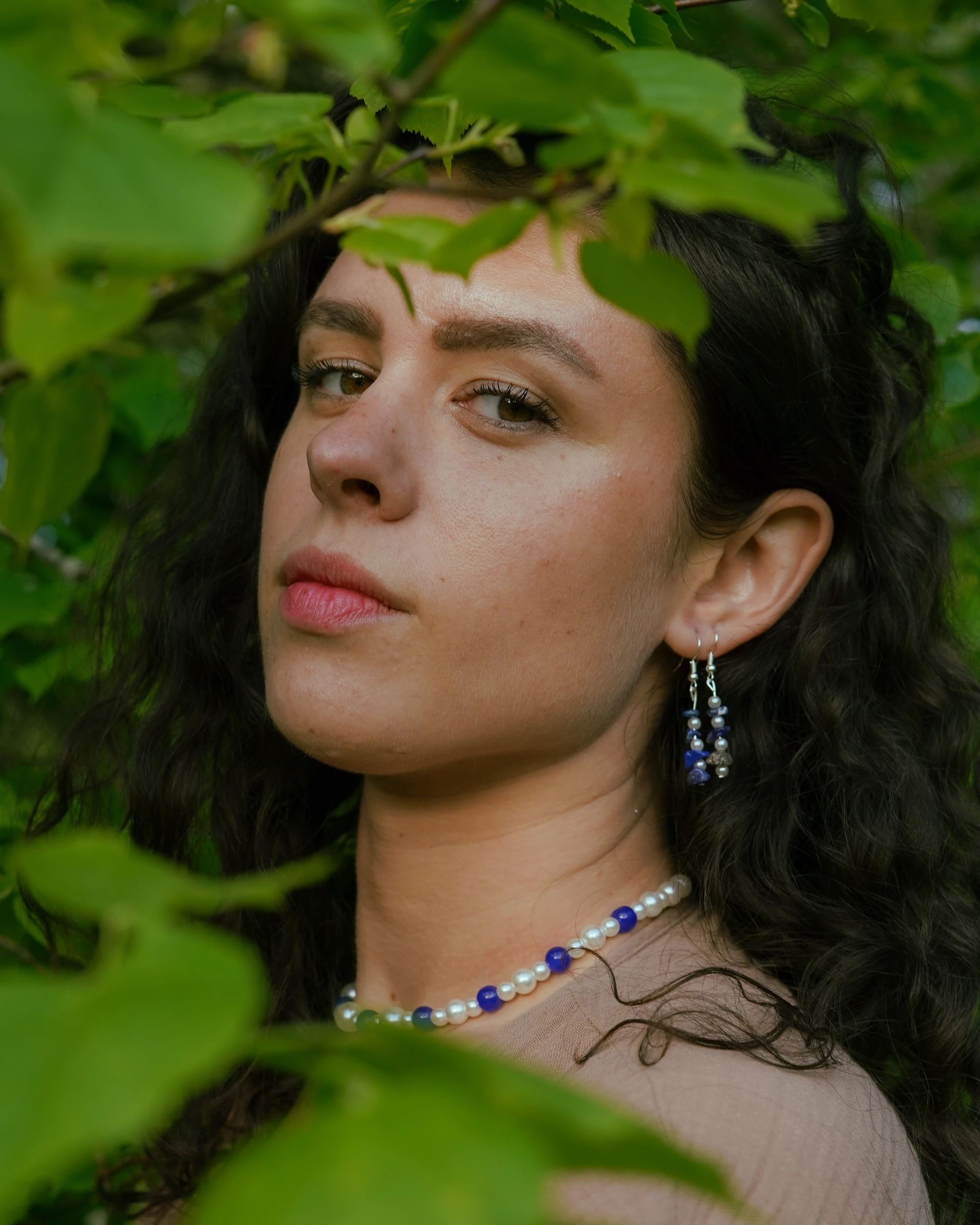 Wildflower Spell portrait framed by leaves with blue and pearl jewellery by Lunar Lens Creative Agency