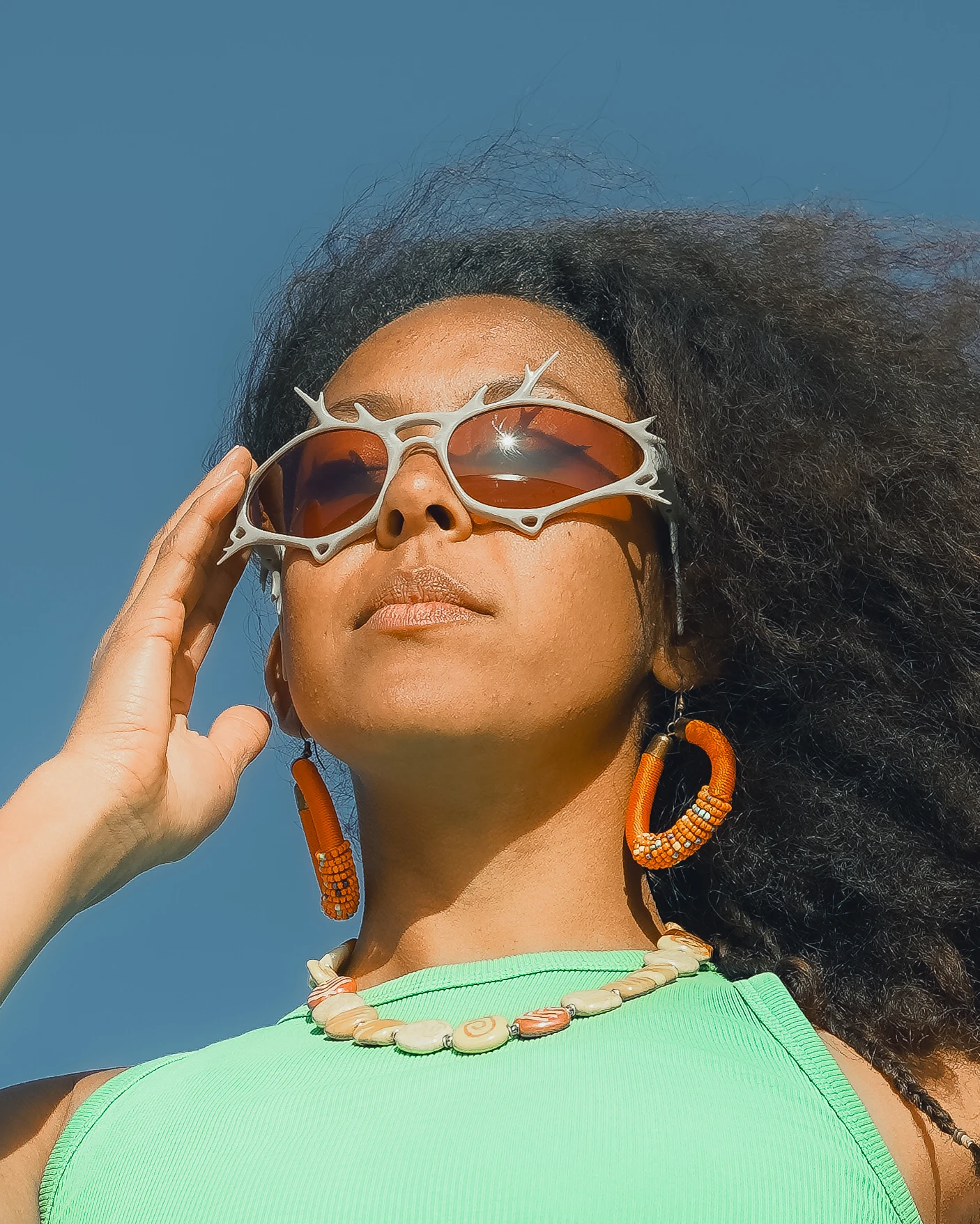 ITURA Studio sunglasses portrait with orange earrings against blue sky by Lunar Lens Creative Agency