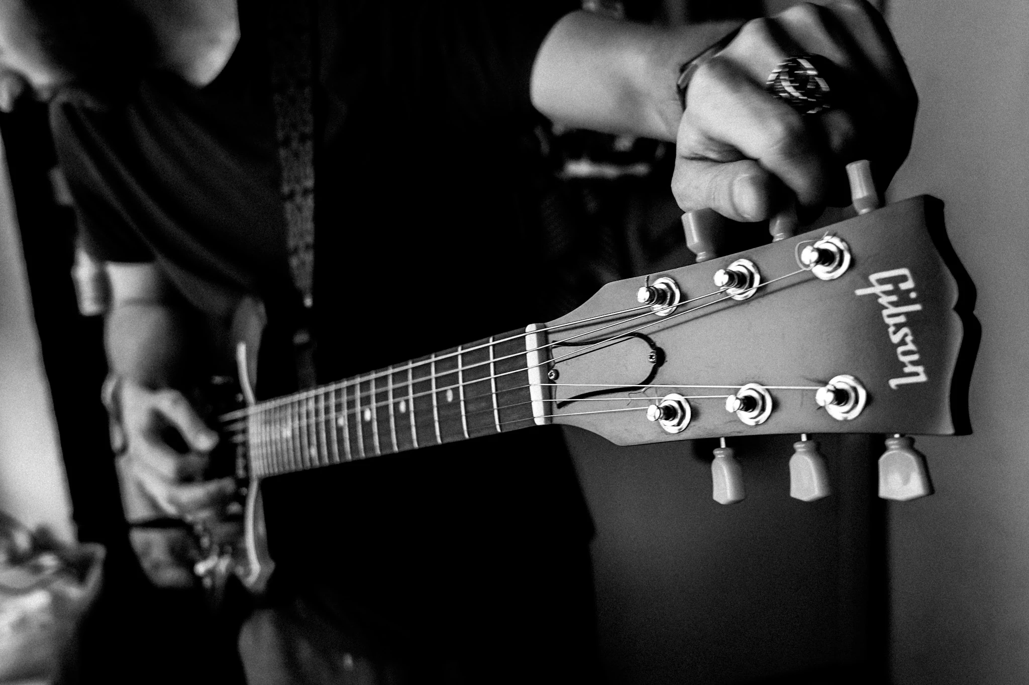 Black-and-white close-up of a guitarist tuning a Gibson guitar by Lunar Lens Creative Agency