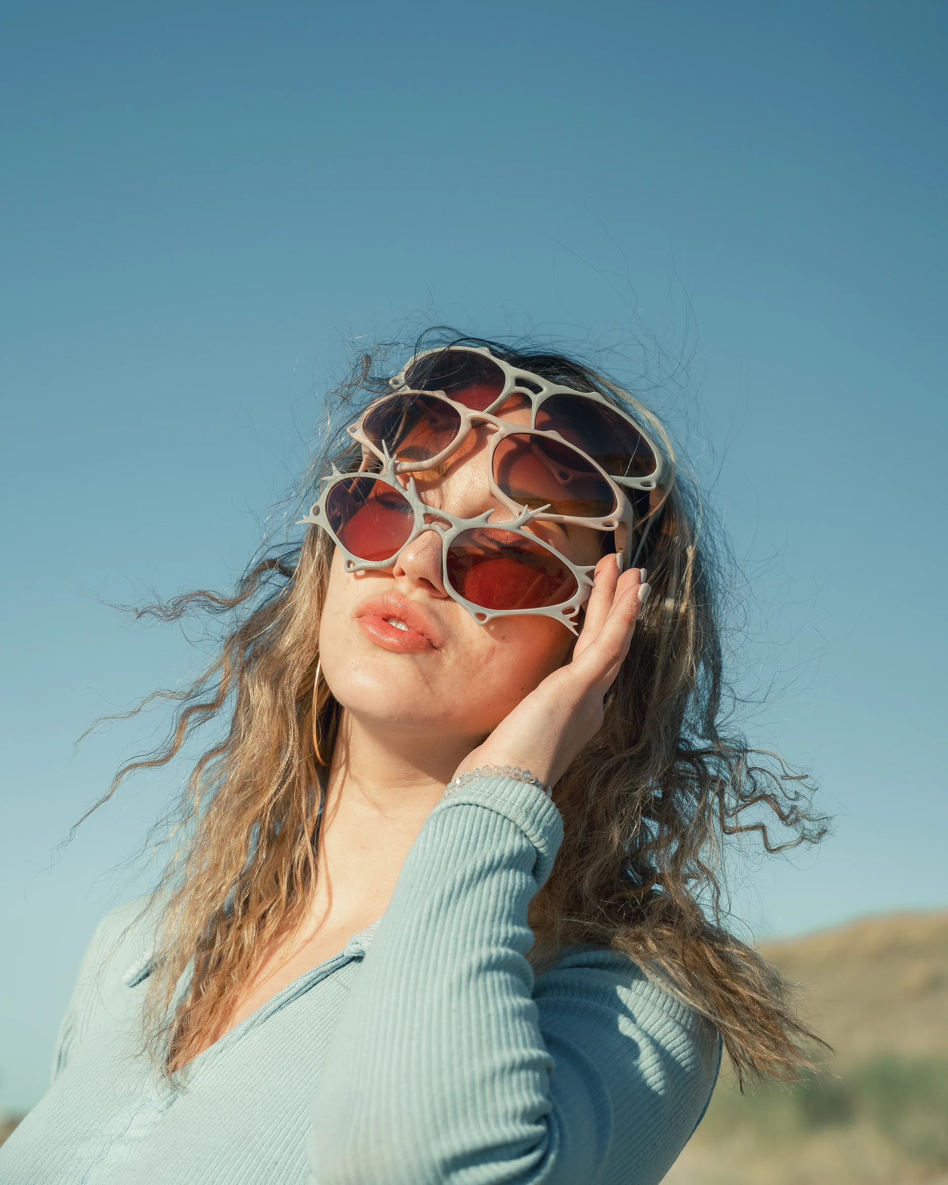 ITURA Studio sunglasses campaign portrait with layered eyewear against blue sky by Lunar Lens Creative Agency