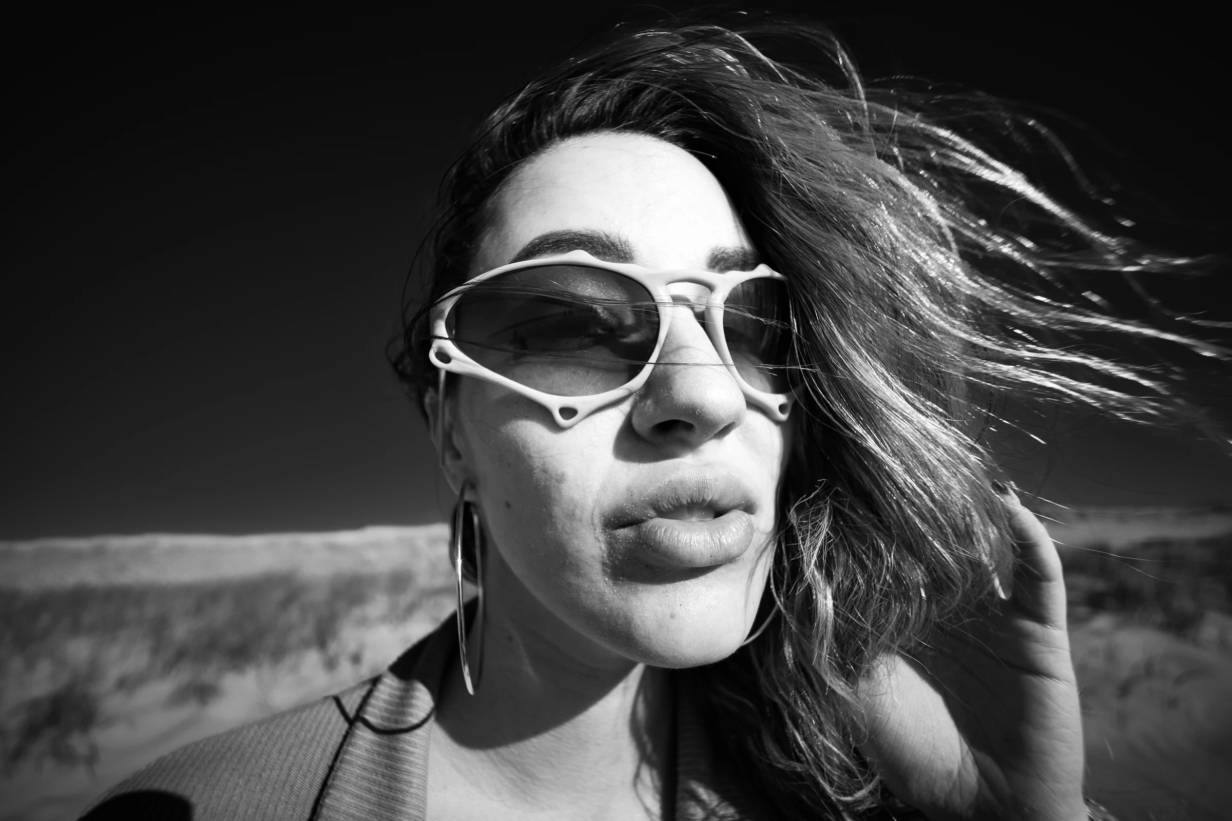 Black-and-white ITURA Studio eyewear portrait with windblown hair by Lunar Lens Creative Agency